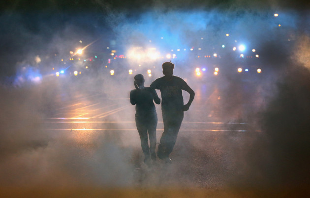 FERGUSON, MO - AUGUST 17:  A woman is helped from the street after bing overcome by tear gas when a demonstration over the killing of teenager Michael Brown by a Ferguson police officer was attacked by police August 17, 2014 in Ferguson, Missouri. Despite the Brown family's continued call for peaceful demonstrations, violent protests have erupted nearly every night in Ferguson since his August 9, death.  (Photo by Scott Olson/Getty Images)